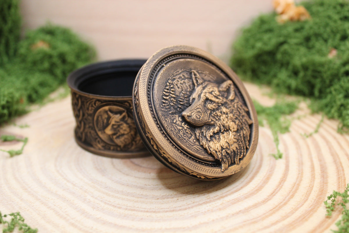Cajita cilíndrica del lobo en dorado con la tapa apoyada, mostrando el hueco interior — Distrito Makers