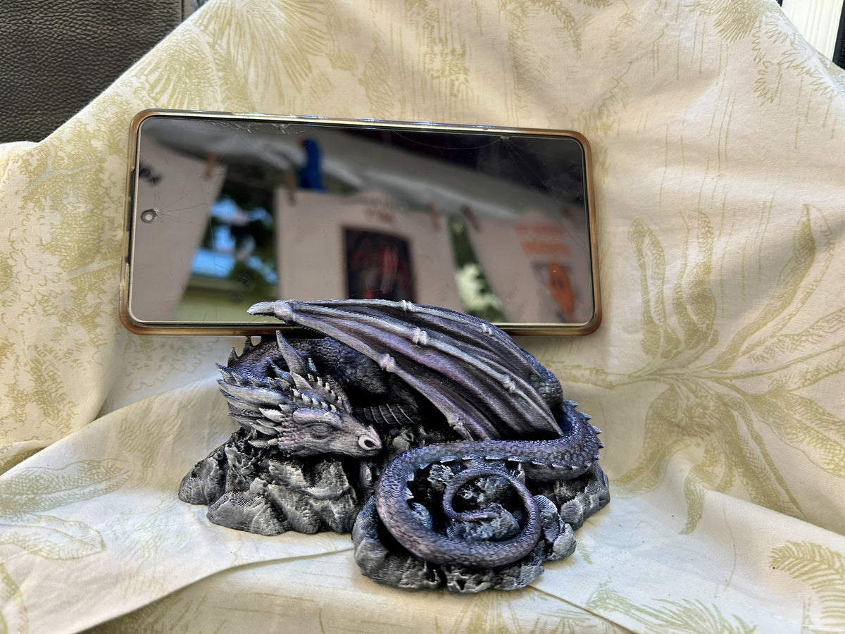 El soporte en uso, con un móvil apoyado en horizontal sobre el dragón — Distrito Makers