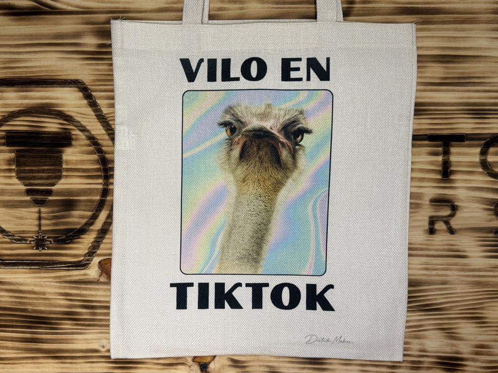 Tote bag de tela símil lino con el lema en asturiano «Vilo en TikTok» y la foto de un avestruz sobre fondo holográfico