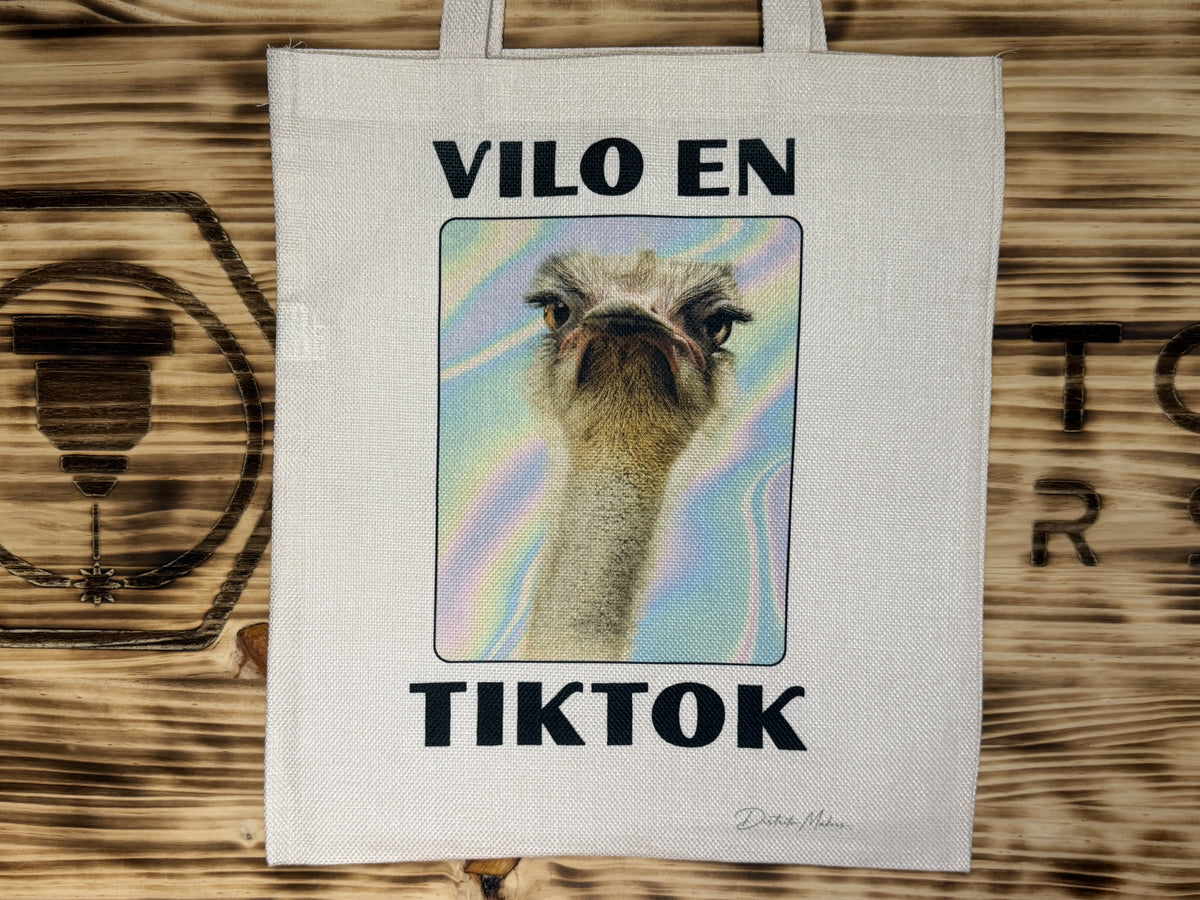 Tote bag de tela símil lino con el lema en asturiano «Vilo en TikTok» y la foto de un avestruz sobre fondo holográfico