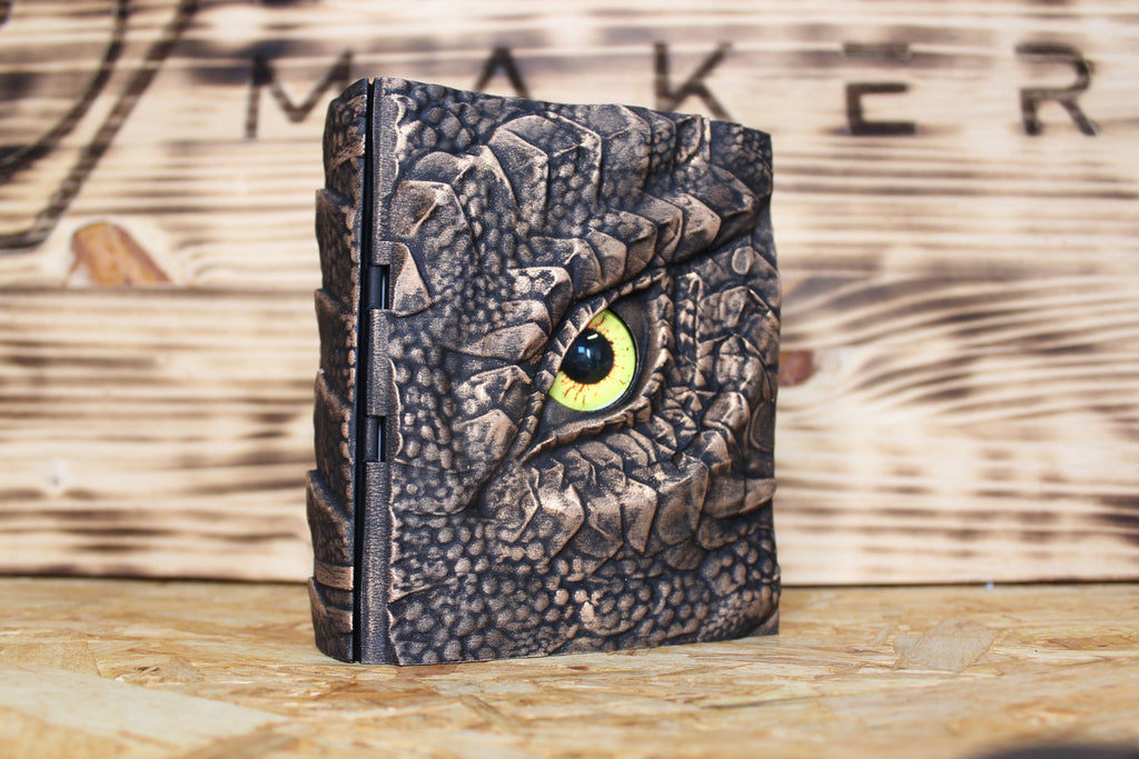 Caja secreta El Ojo del Cuélebre en dorado oscuro, con un ojo de dragón amarillo