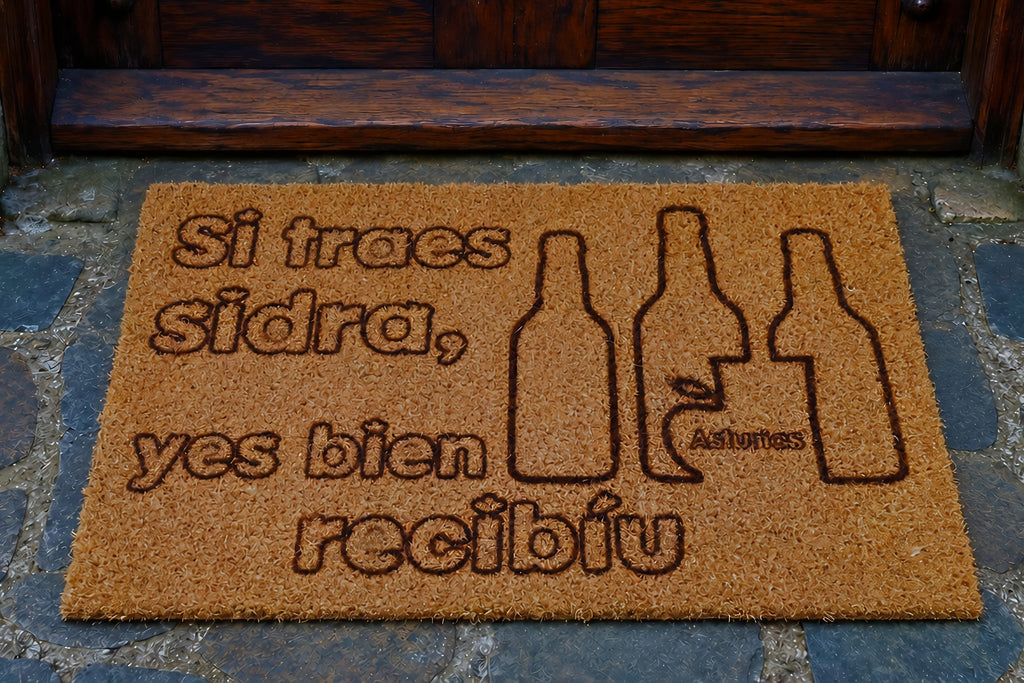 Felpudo de coco con tres botellas de sidra grabadas y la frase Si traes sidra, yes bien recibíu — Distrito Makers